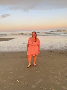Picture of a woman standing in front of the water on a beach